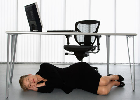 Kvinna som sover under skrivbordet