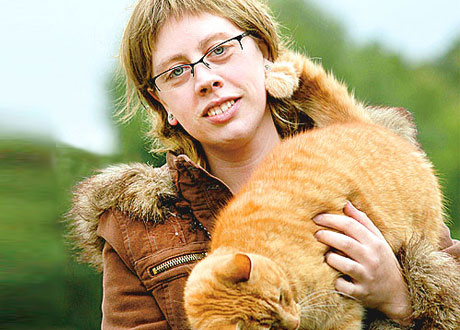 Susanne med sin katt mot grönskande utomhusbakgrund