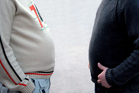 Två män visar sina feta tröjbeklädda magar i profil