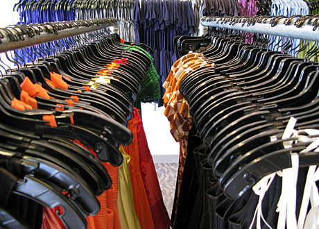 Kläder hänger på hängare i rader i affär