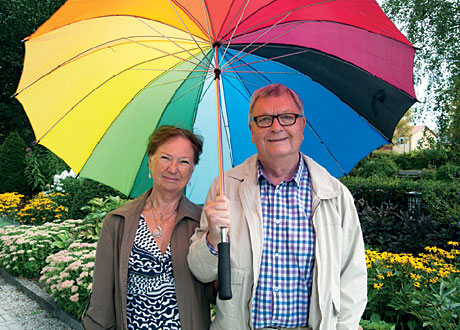 Paret står utomhus under ett gigantiskt färgglatt paraply