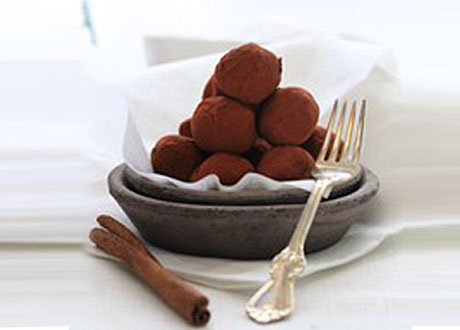 Chokladtryffel lagda på hög i en skål bredvid vikta servetter och kanelstång