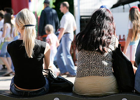 Två flickor sitter med ryggen mot kameran i en folkmassa