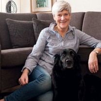 Karin sitter på golvet framför soffan med sin hund