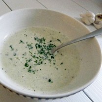 Kronärtskockssoppa med mascarpone serverad i vit djup skål med sked och persilja som garnering