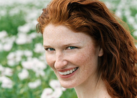Lycklig kvinna med rött, tjockt hår