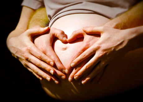 Gravid mage med händer på