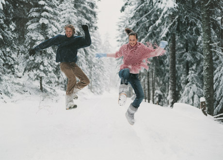 Ett glatt par som hoppar i snön