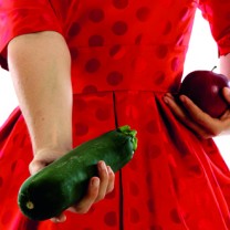 Man ser livet på kvinna i röd klänning som håller en zucchini och ett äpple