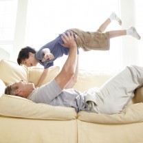 Pappa leker med sin son ligger på soffan slänger upp sonen i luften