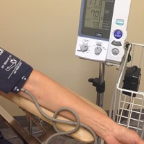 En person gör blodtrycksmätning med maskin, endast armen och maskinen syns