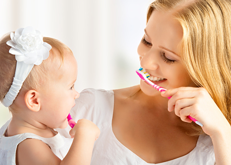 Mamma och flickbebis borstar tänderna