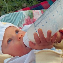 Bebis håller i och suger på nappflaska