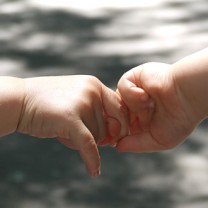 Två små barnhänder håller i varandra