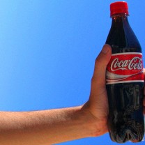 En hand håller i en coca-cola-flaska