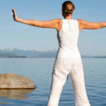 kvinna i vitt gör yogapose vid vatten
