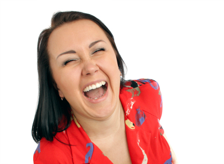 Mörkhårig kvinna i röd topp skrattar stort