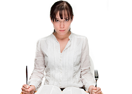 Kvinna sitter redo med kniv och gaffel
