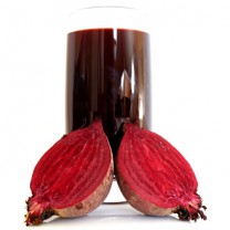 Glas med rödbetsjuice bredvid två rödbetshalvor