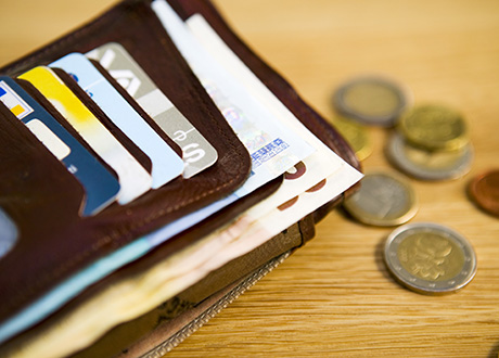 Plånbok med kort och sedlar, euro-mynt bredvid på bordet