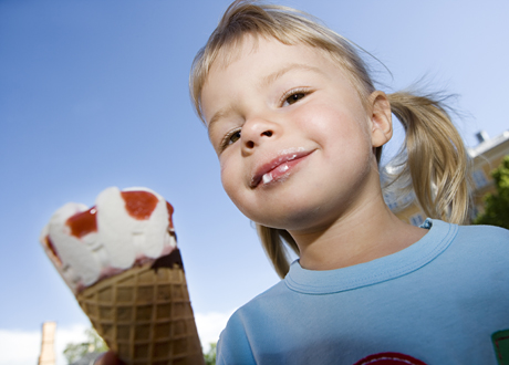 åttaårig flicka äter glass i strut