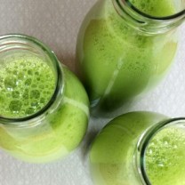 Tre glasflaskor fyllda med grönjuice