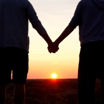 Par håller handen i solnedgång