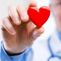 man med läkarrock och stetoskop håller upp rött hjärta
