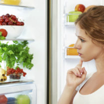 kvinna funderar på vad som finns i kylskåpet