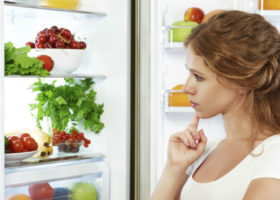 kvinna funderar på vad som finns i kylskåpet