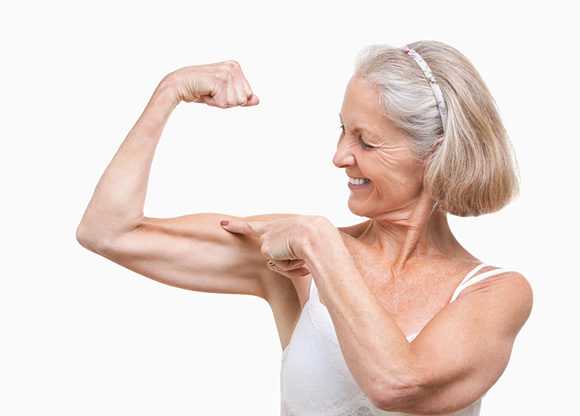 Äldre kvinna spänner sin biceps