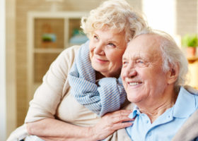 Äldre par ler och håller om varandra