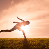 Person hoppar utomhus i siluett mot solen