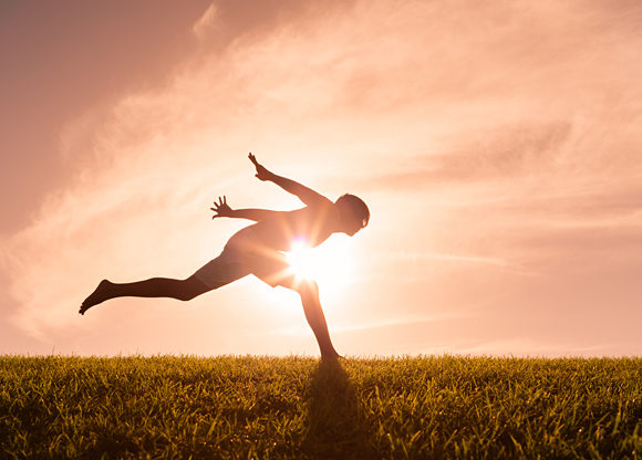 Person hoppar utomhus i siluett mot solen