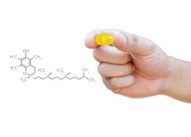 hand håller e-vitaminkapsel intill animerad kemiformel