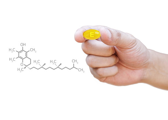 hand håller e-vitaminkapsel intill animerad kemiformel