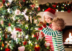 julgran som pyntas av två små barn