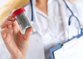 Kvinna i läkarrock håller cannabis i burk