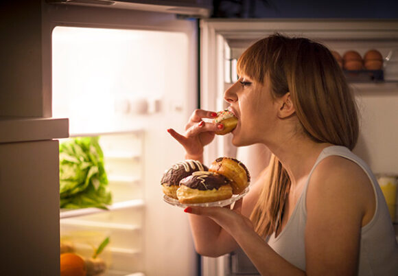kvinna äter från kylskåpet