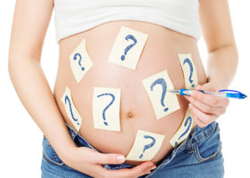 Gravid kvinna som målat frågetecken på magen
