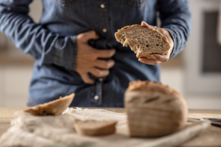 Närbild på person med bröd i handen som håller sig för magen