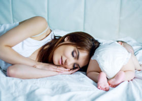 mamma sover bredvid bebis i blöja