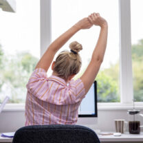 kvinna stretchar framför skrivbordet