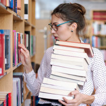 Kvinna håller trave böcker på bibliotek