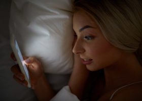kvinna som tittar på sin mobil i sängen