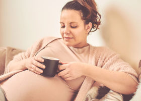 Gravid kvinna dricker kaffe
