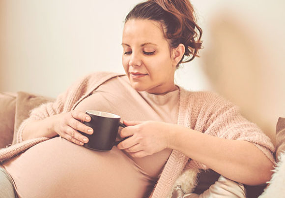 Gravid kvinna dricker kaffe