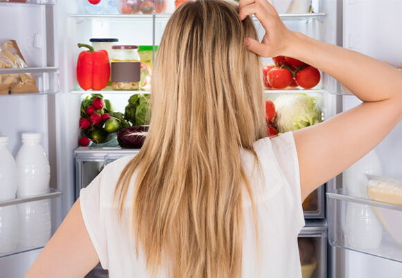 Kvinna tittar in i öppet kylskåp