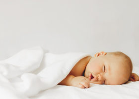 Bebis som sover under vit filt