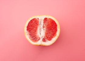 En grapefrukt isolerad på rosa bakgrund, metafor för det kvinnliga könsorganet